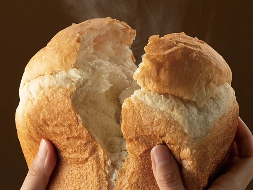写真：パンを手で半分に割いている様子