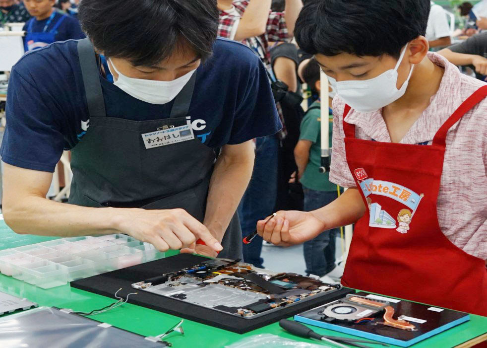 参加者のこどもがエンジニアに教わりながらレッツノートを組み立てている様子
