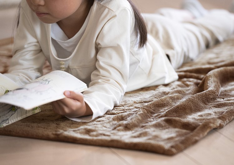 写真：子供が電気ひざかけ くるけっとを床に敷いて使用するイメージ
