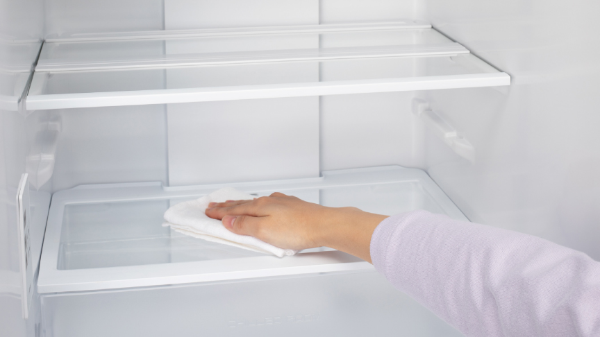 画像：冷蔵庫内のガラス棚を布巾で拭いている様子