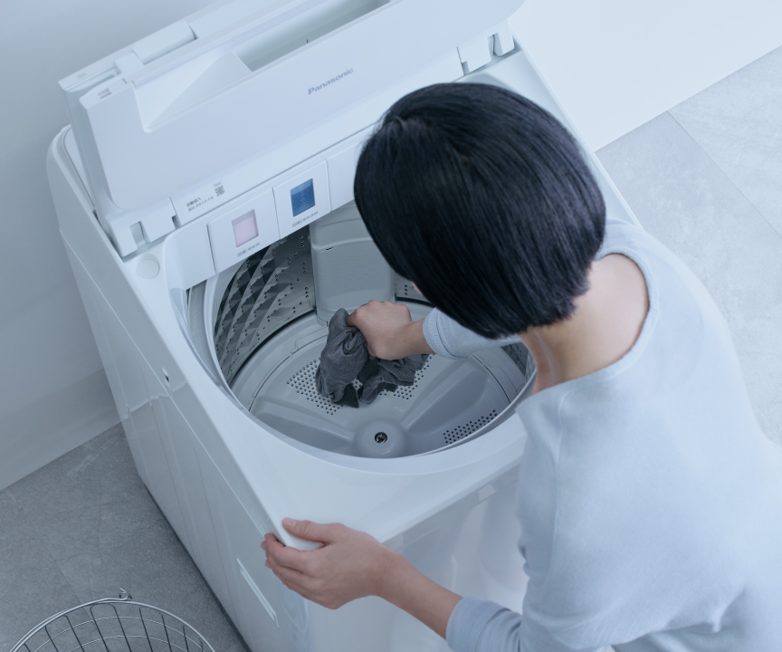 洗濯槽の底の衣類を取り出しているイメージ