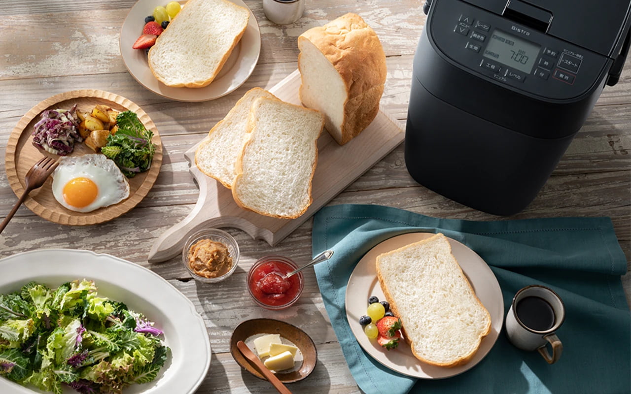 写真：ホームベーカリー ビストロ SD-MDX4、パン、サラダ、フルーツ、コーヒー、ジャム等が置かれている様子