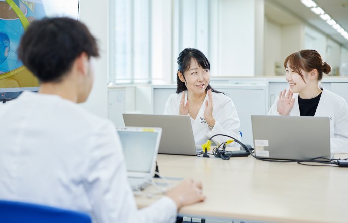 写真：パソコンを開きながら、伊藤晶子さんと白衣を着た女性が話している様子