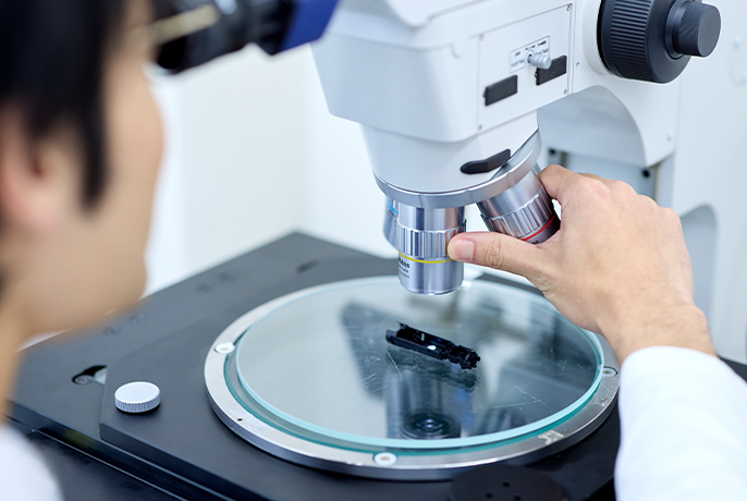 写真：顕微鏡を覗いている坂本滉大さんの手元