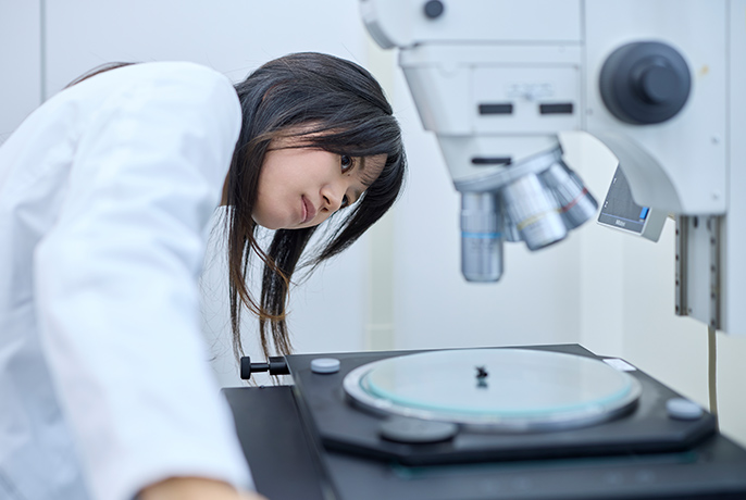 写真：顕微鏡装置に向かって作業している黒塚彩さん