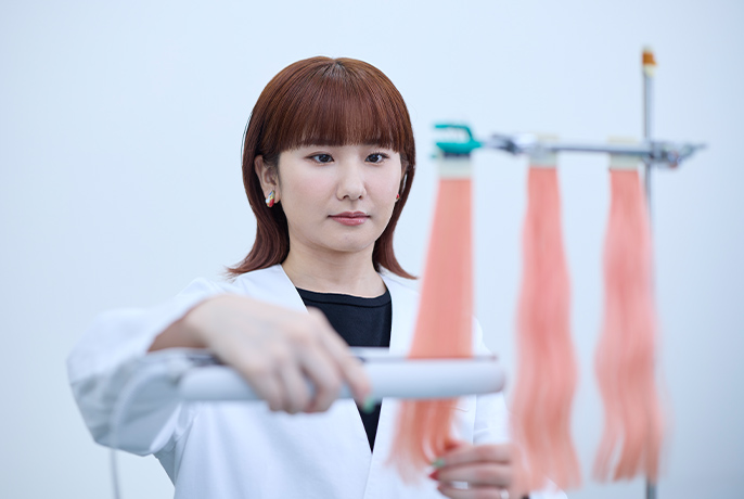 ヘアアイロンをサンプルの髪にあて評価している豊田真央さん