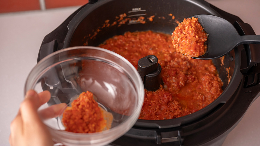 写真：鶏ミートソースを取り分けているようす