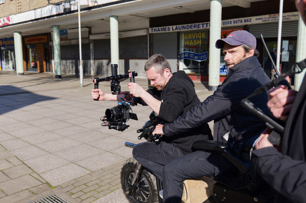 ドライバーが操る小型車に乗ってジンバルに装着したLUMIX S5ⅡXを操作する、撮影監督フランクリン・ダウ／Franklin Dow氏。