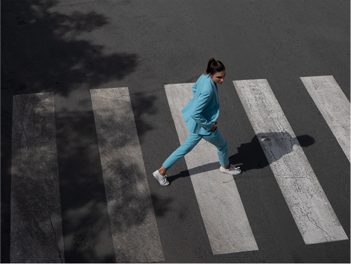 画像：横断歩道を颯爽と渡る水色のジャケットの女性