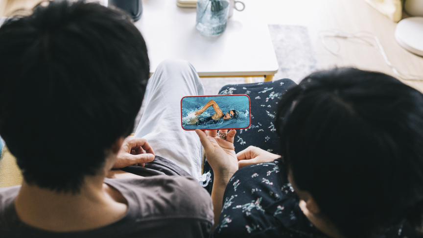 スマートフォンでスポーツ観戦をする夫婦