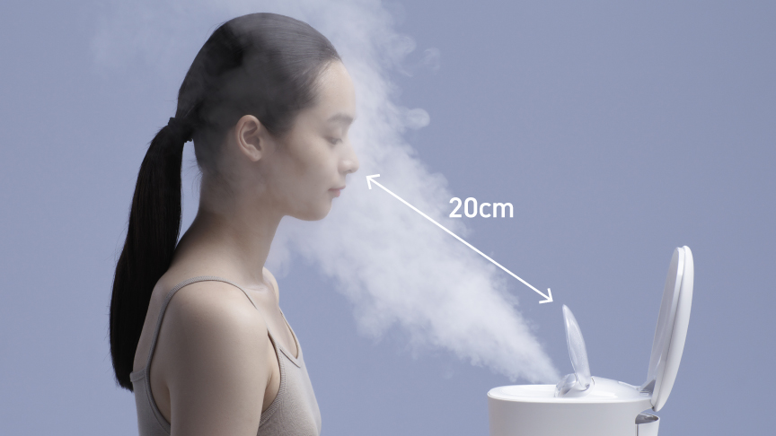 写真：ノズルガードの先端から20 cm以上離して、スチームを浴びる女性