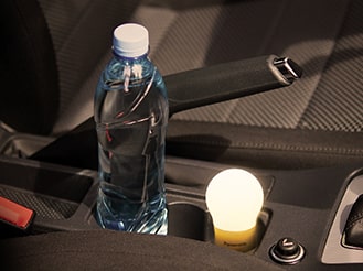 暗い車内に置いてある球ランタン、ドリンクホルダーに置いてあるペットボトルの写真