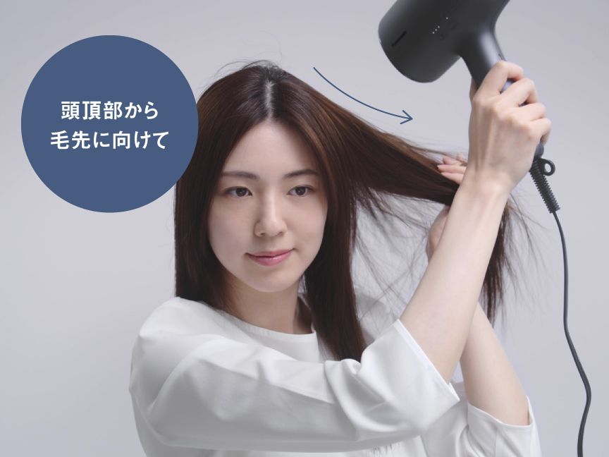 写真：頭頂部から毛先に向けて温風・冷風をあてている写真