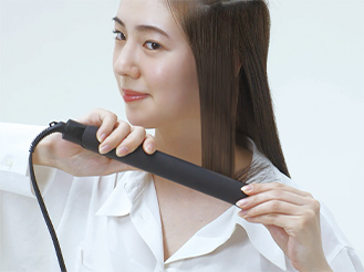 写真:［3］コンパクトストレートアイロンを毛先に向かってすべらせる女性の様子