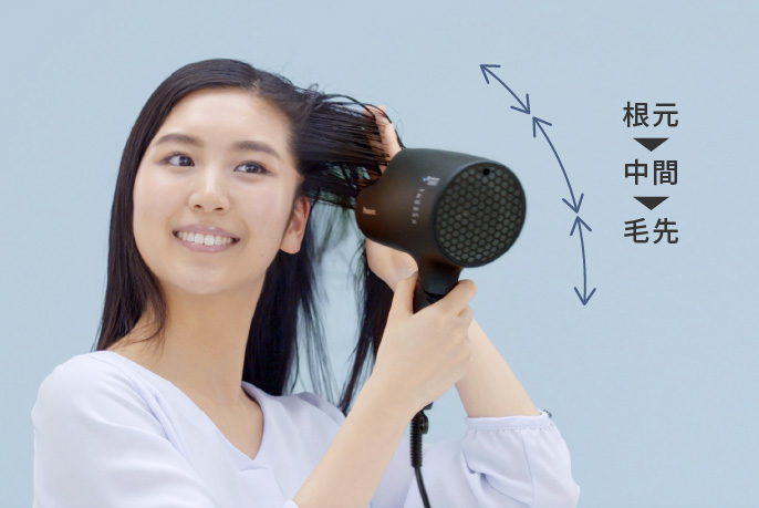 【写真】ドライヤーで髪を乾かしている女性（根元→中間→毛先の順で乾かす）