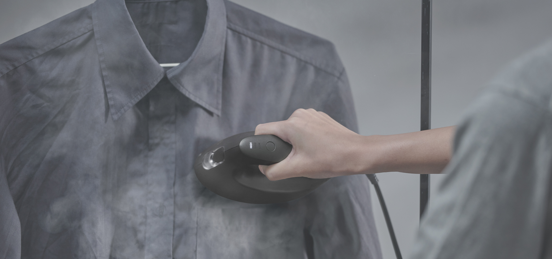 ハンガーにかけたシャツを衣類スチーマーでケアしている写真