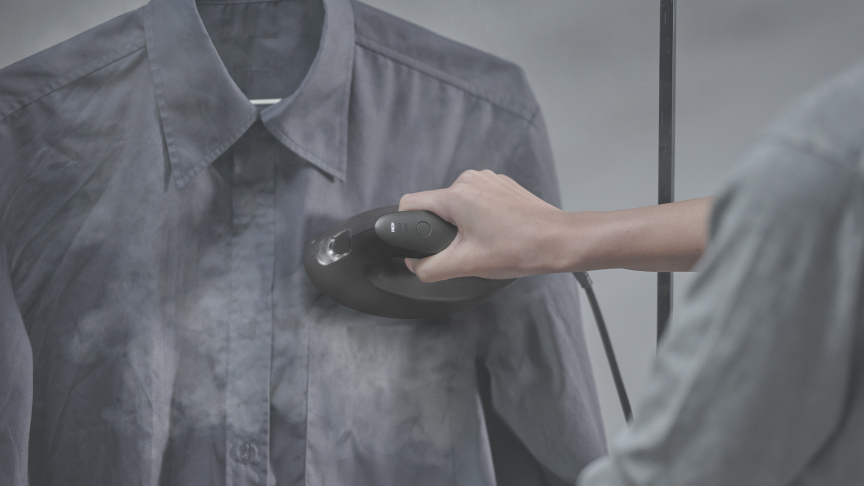 ハンガーにかけたシャツを衣類スチーマーでケアしている写真