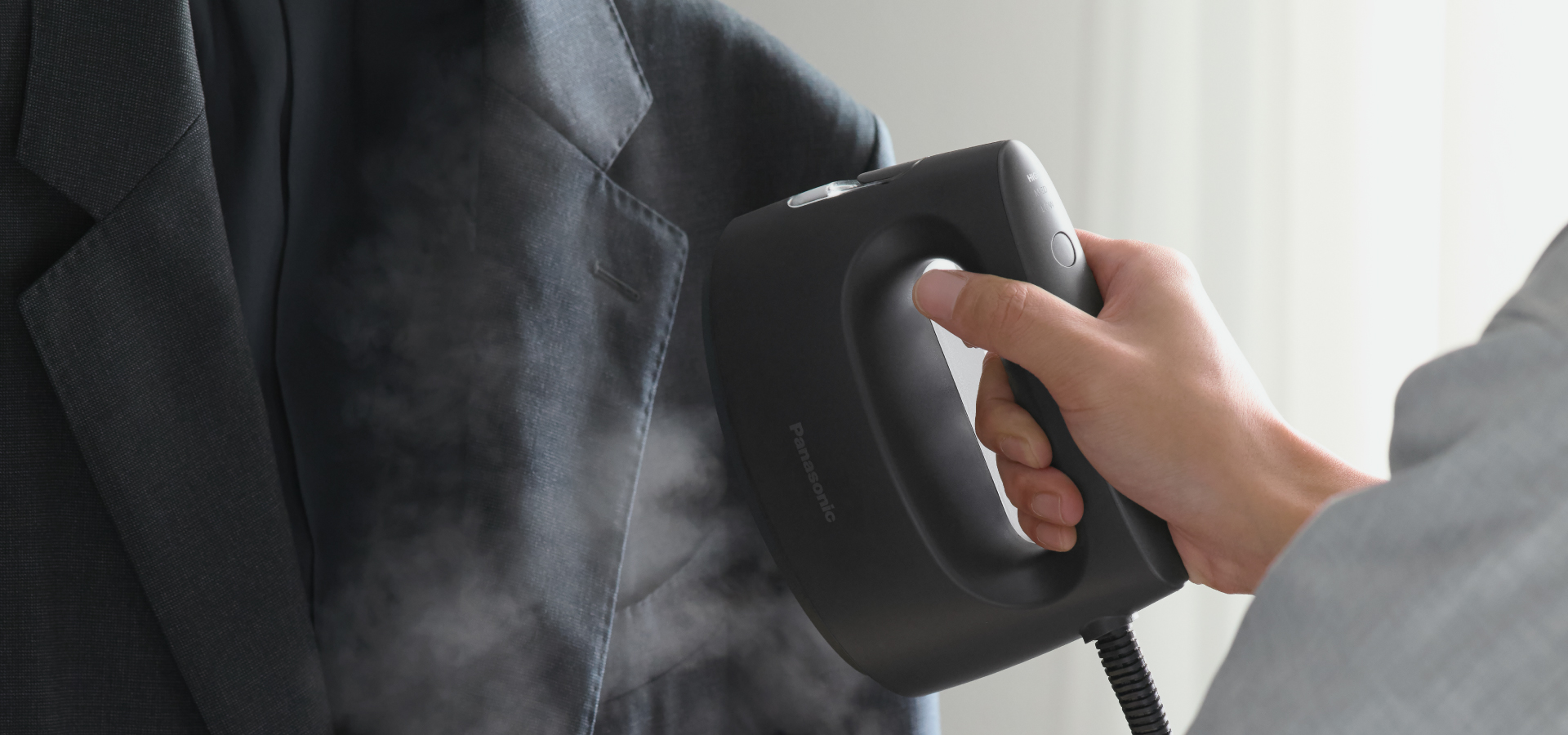 衣類スチーマーでハンガーにかけたジャケットをケアしている写真