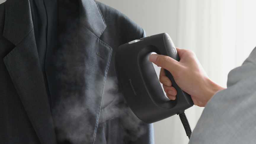 衣類スチーマーでハンガーにかけたジャケットをケアしている写真