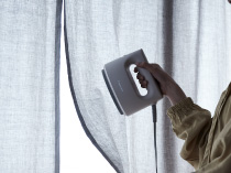 カーテンに衣類スチーマーをあてる様子