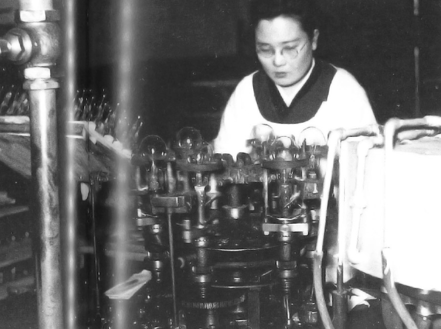 京都電球工場の作業風景 慎重を要する手仕事が主体でしたが、戦前に比べて徐々に機械化が進んでいきました。
