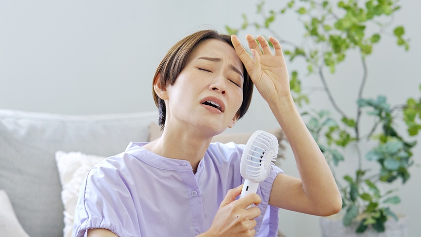 ハンディファンを使っている暑そうな女性の写真