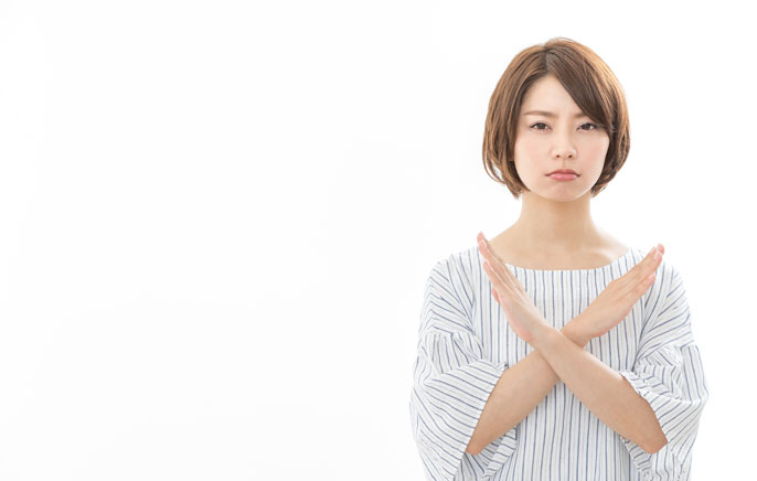 腕でバツをしている女性の写真