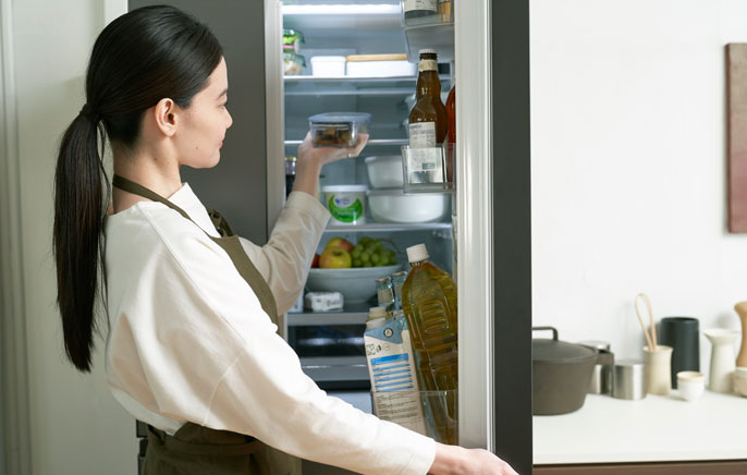 写真：冷蔵庫の中を確認する女性