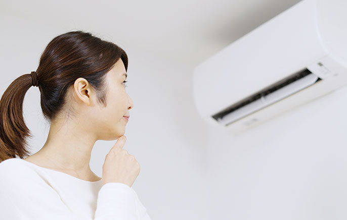 写真：エアコンを見つめる女性