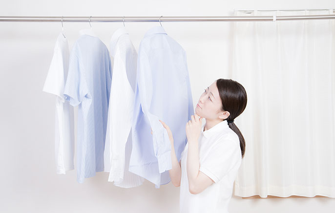 部屋干しした洗濯物を見つめる女性の写真