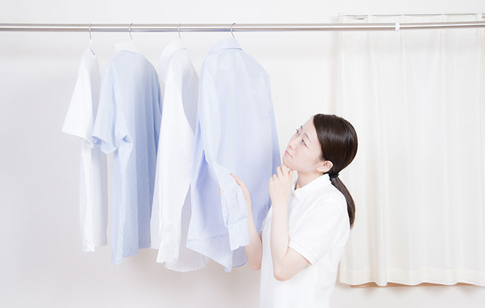写真：部屋干しした洗濯物を見つめる女性