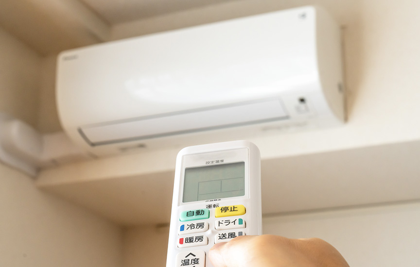 写真：エアコンにリモコンを向けるイメージ