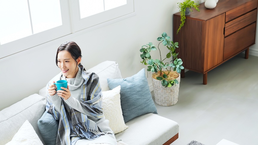写真：エアコンを活用して冬を快適そうに過ごす女性のイメージ
