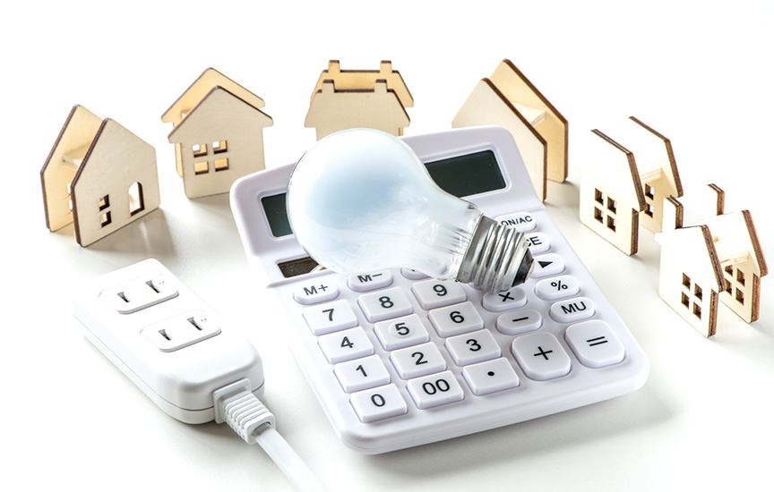 写真：電卓と電球と家の模型とコンセント