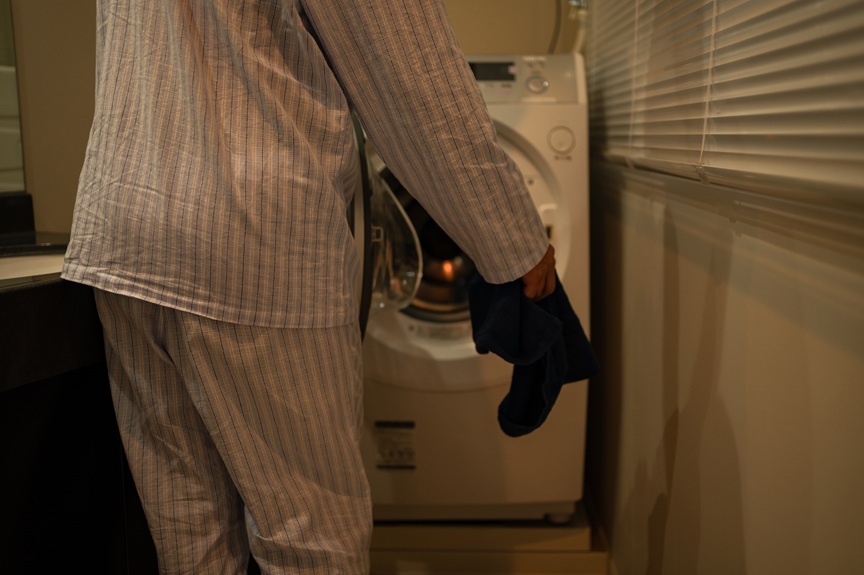 洗濯機に洗濯物を入れている人の写真