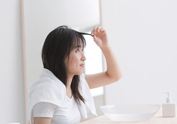 写真：お風呂上がりの女性が前髪を気にしているイメージ