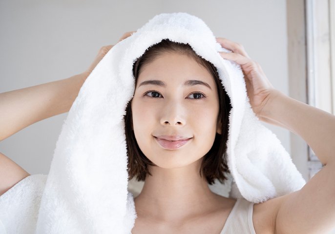 写真：タオルで髪を乾かす笑顔の女性
