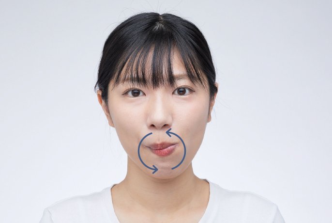 写真：口を閉じるて舌先を鼻の下にある歯と唇の間におき、ほうれい線を舌で口の中からなぞるように、右回りで円を描きながらゆっくりと動かすイメージ