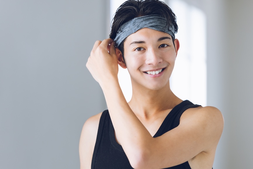 ヘアバンドを付けて笑顔を見せる男性の写真
