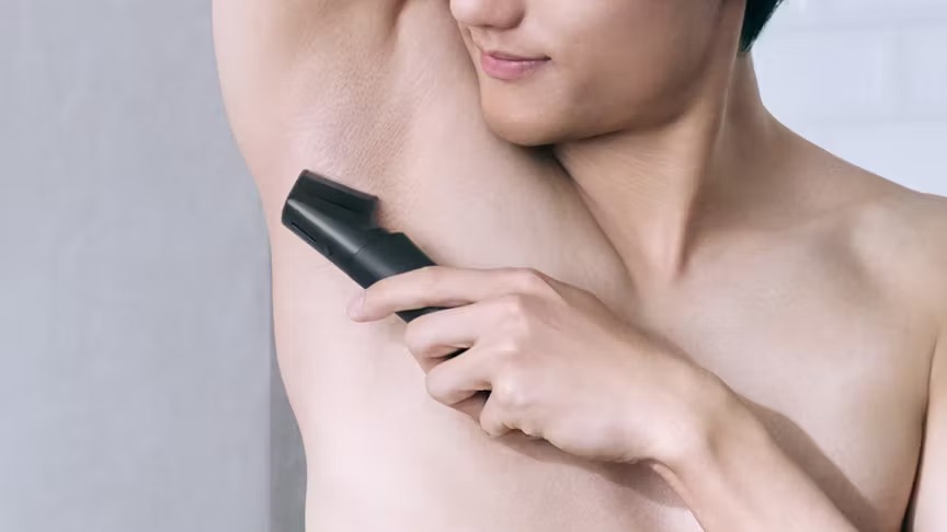 脇毛をボディトリマーで手入れしている男性の写真