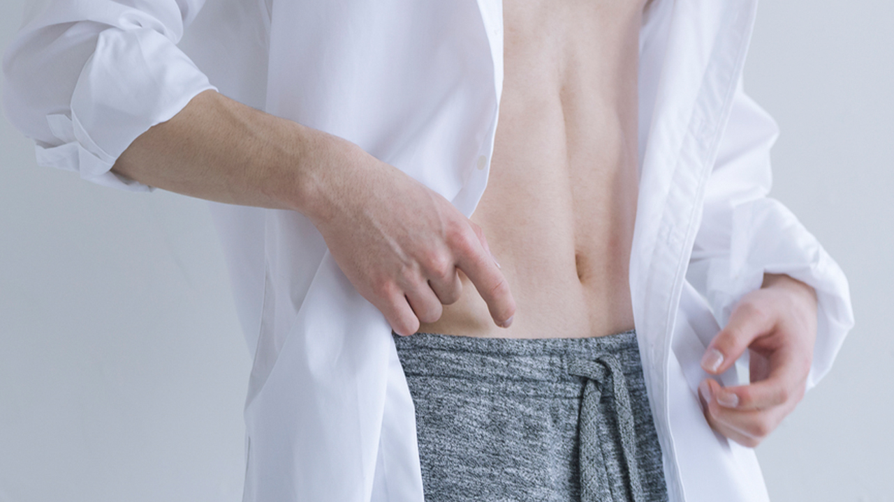 シャツを羽織ってお腹を見せている男性の写真
