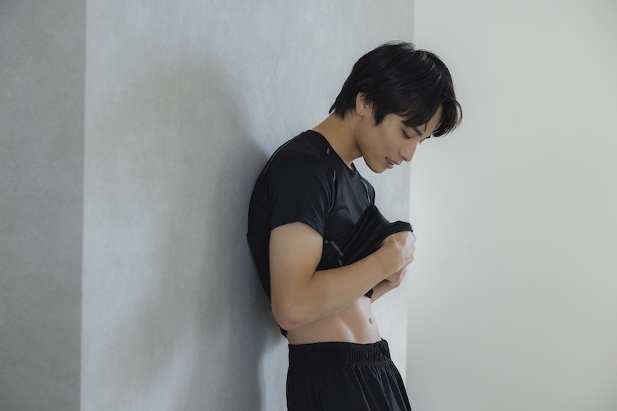 壁にもたれてお腹を確認している男性の写真