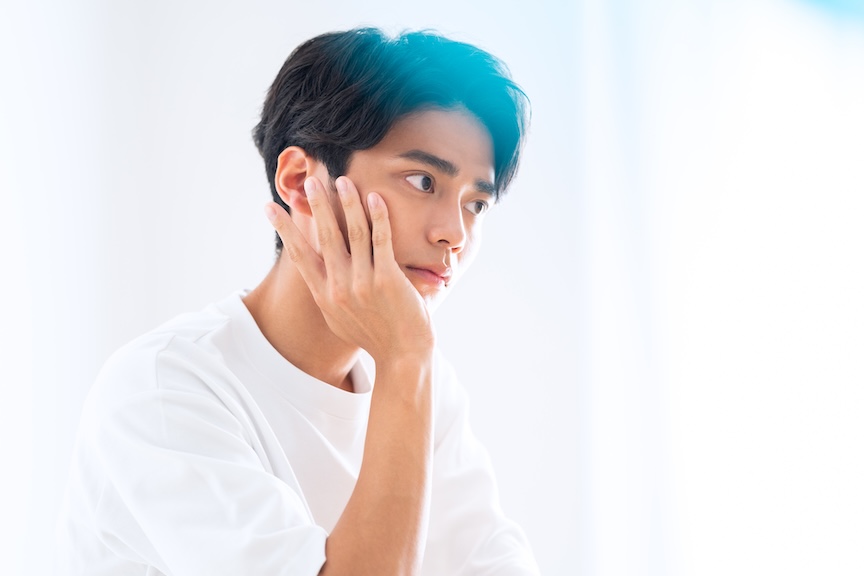 自分の頬に手を当てている男性の写真