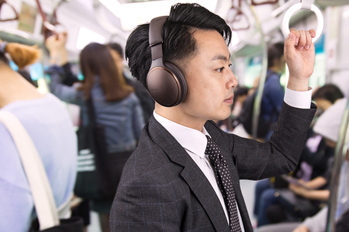 写真：男性が電車内でヘッドホンを装着している様子