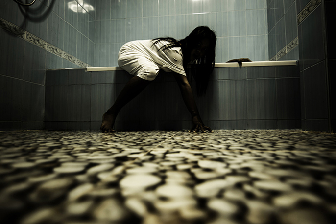 写真：暗い浴室で湯船から這い出る女性