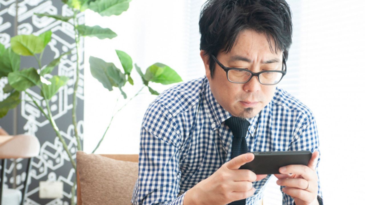 スマホでテレビを見ている男性の写真
