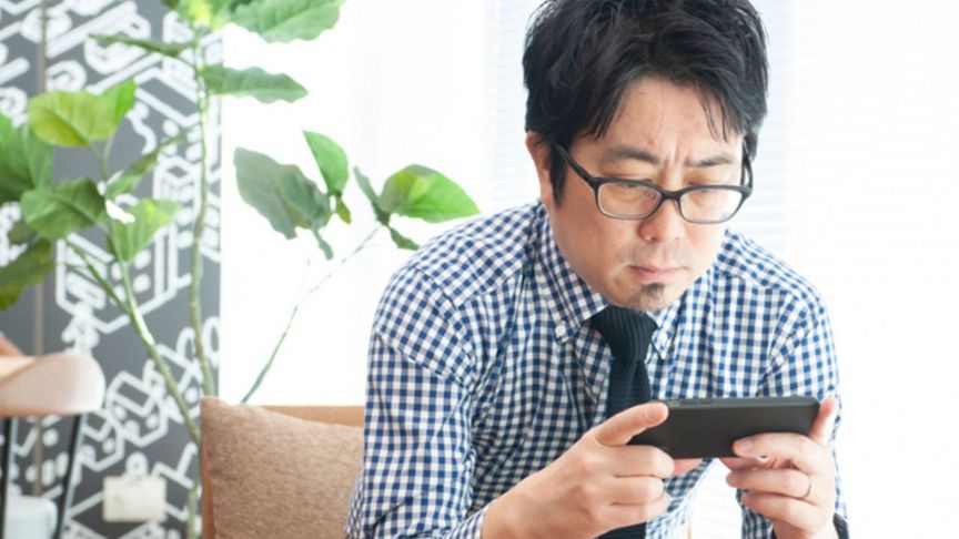 スマホでテレビを見ている男性の写真
