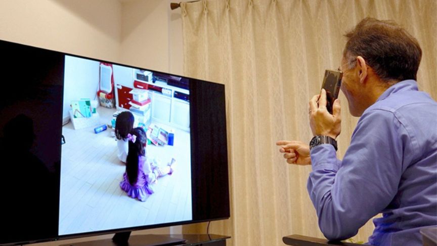 孫の写真をテレビで見ている祖父の写真