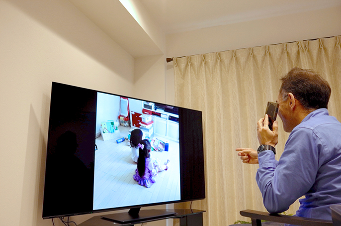 孫の写真をテレビで見ている祖父の写真