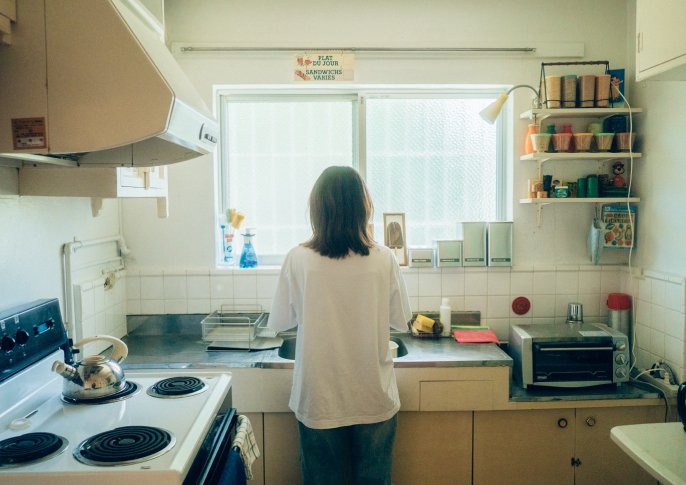 写真：女性がキッチンに立ち料理をしてる後ろ姿のイメージ